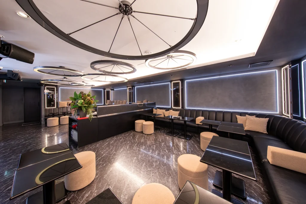 Modern interior of Club Cure in Shinjuku, Tokyo with circular ceiling lights, black marble floor, and sofa seating for guided host club experience