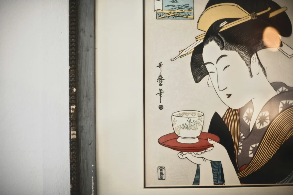 Ukiyo-e style print of a woman holding a tea cup, displayed in a gallery setting